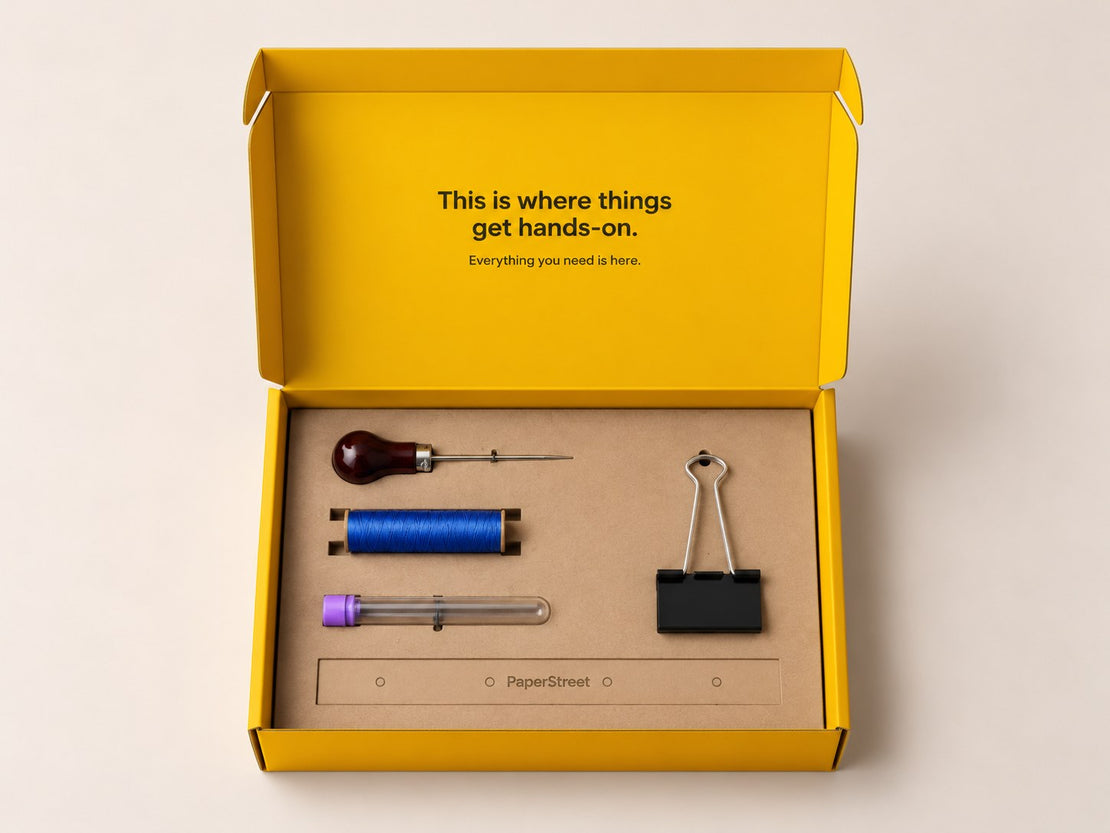 Open yellow Journal Binding Kit with papers, waxed thread, needle, awl and binder clips